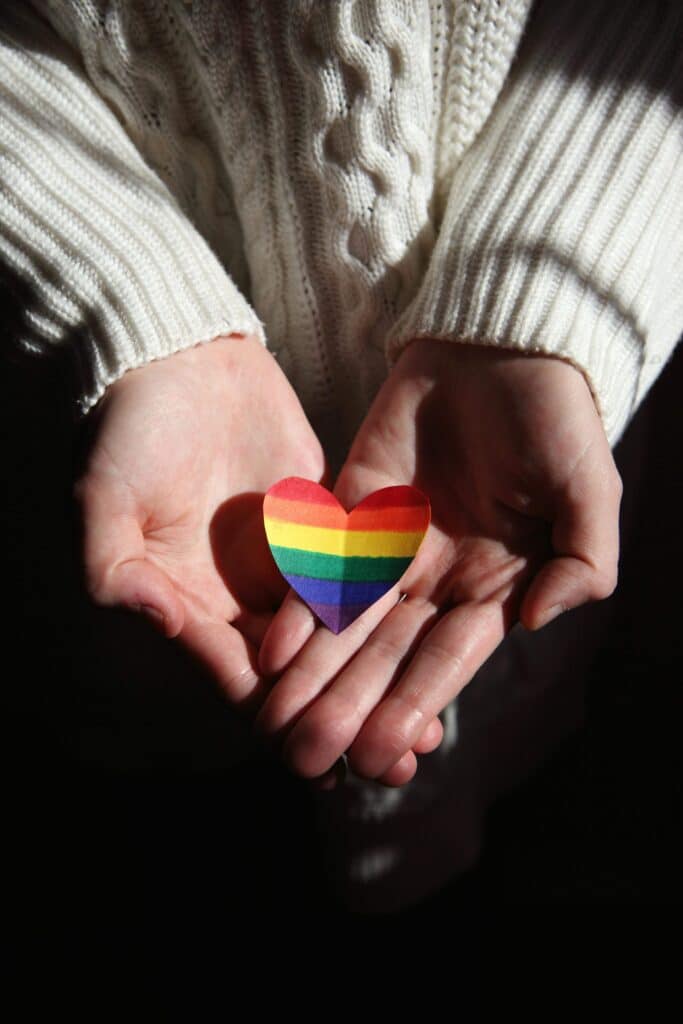 Hand die een regenboog hartje vasthoudt als symbool voor de vraag: ben ik lesbisch?