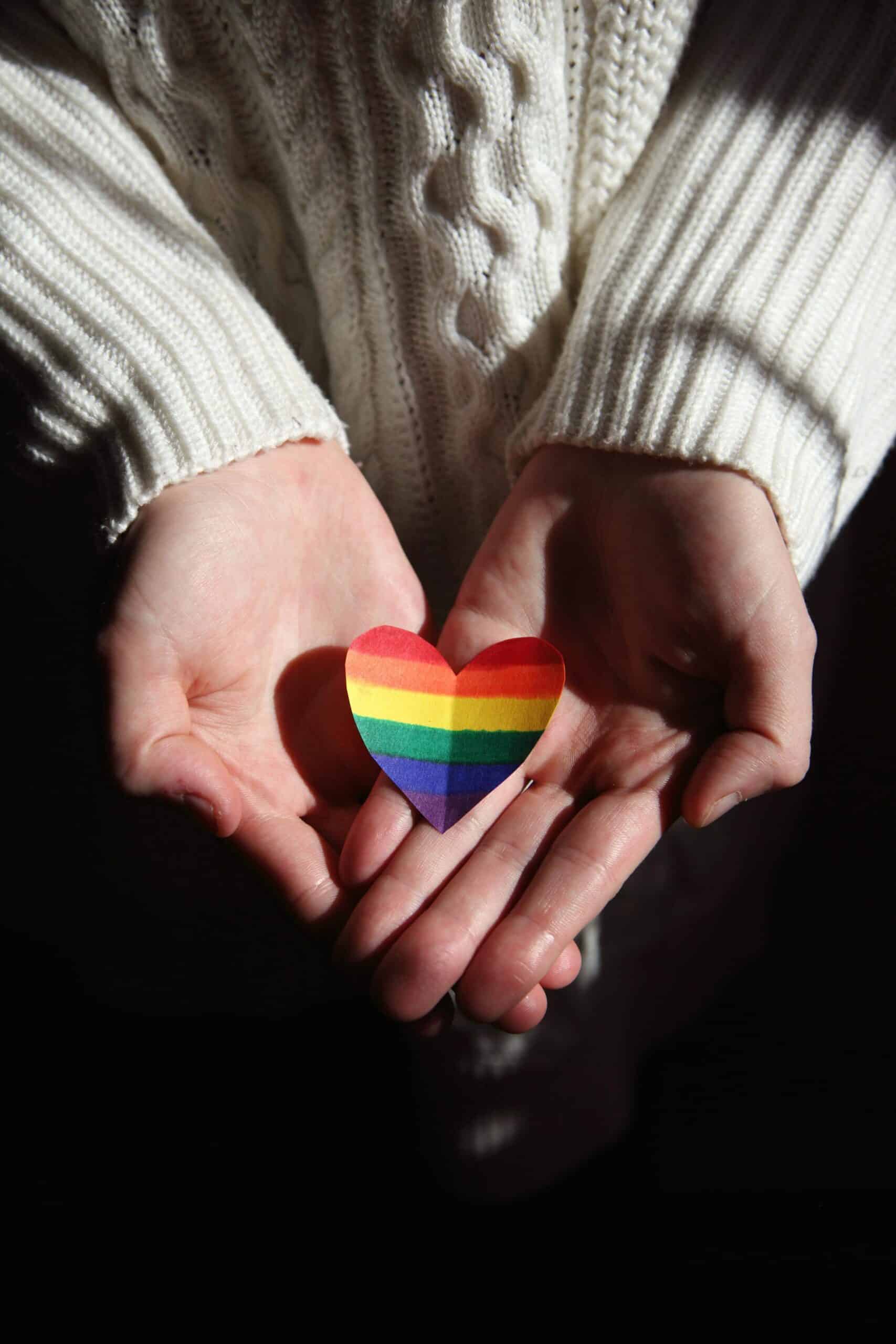 Hand die een regenboog hartje vasthoudt als symbool voor de vraag: ben ik lesbisch?